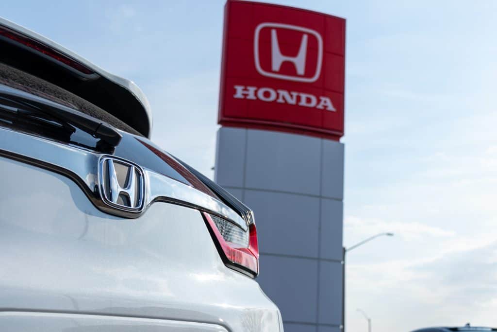 Traseira de um carro da Honda ornando com a fachada de uma concessionária da montadora