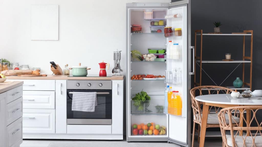 Geladeira aberta cheia de alimentos frescos perto de uma parede branca na cozinha