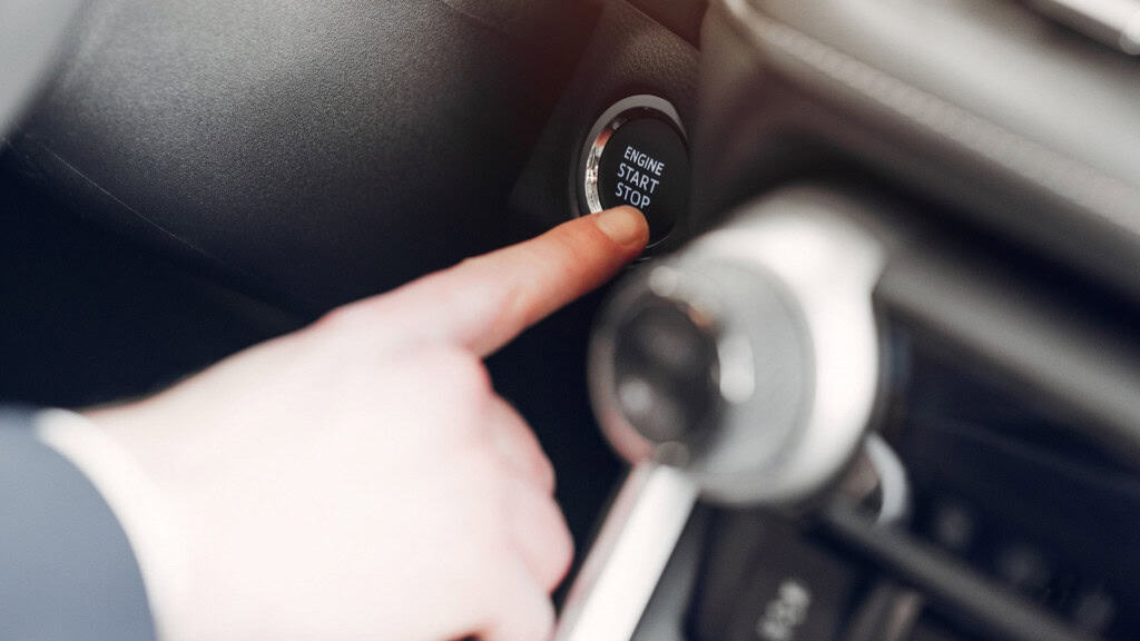 Homem dá partidano carro acionando botão Start/Stop