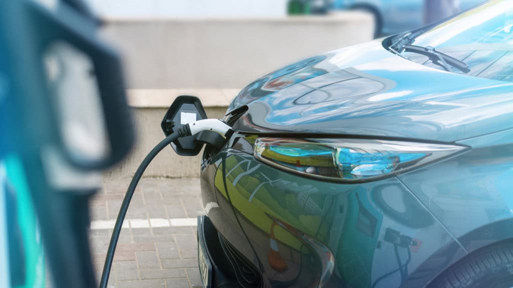 imagem mostra um carro elétrico sendo recarregado em um posto