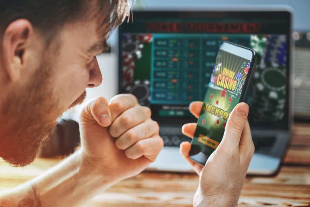 Homem olhando o smartphone e celebrando a conquista de uma aposta