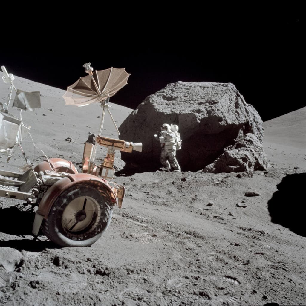 Foto do astronauta Harrison Schmitt trabalhando ao lado de uma enorme rocha ao norte da Lua.