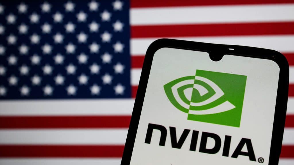 Celular exibindo logomarca da Nvidia na tela na frente de outra tela exibindo bandeira dos Estados Unidos