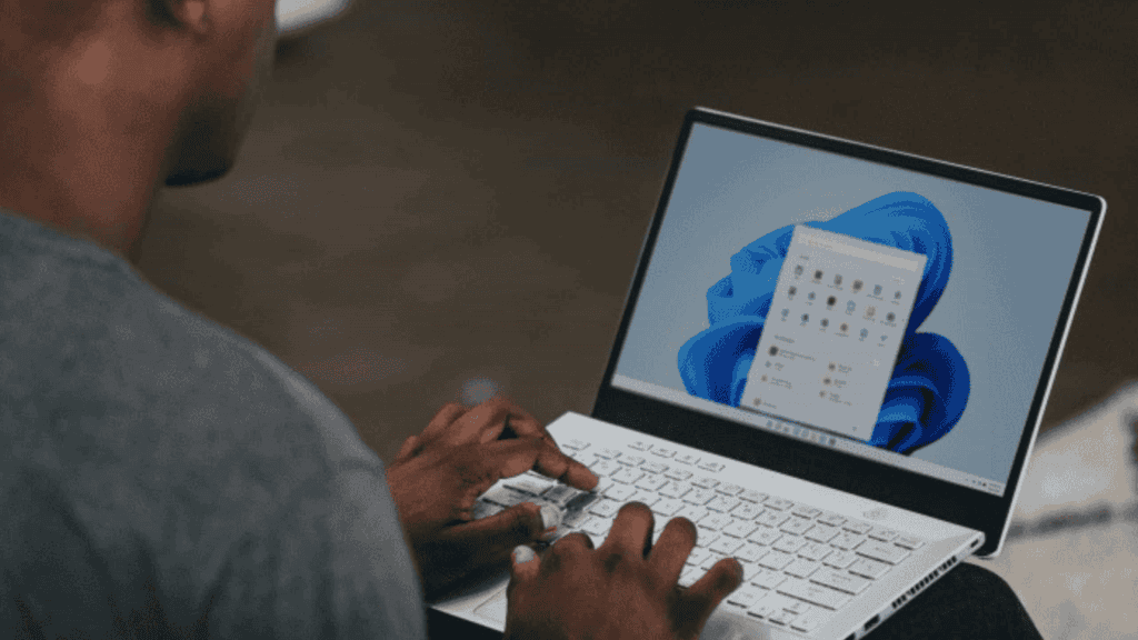 Homem mexendo em um notebook cujo sistema operacional é o Windows