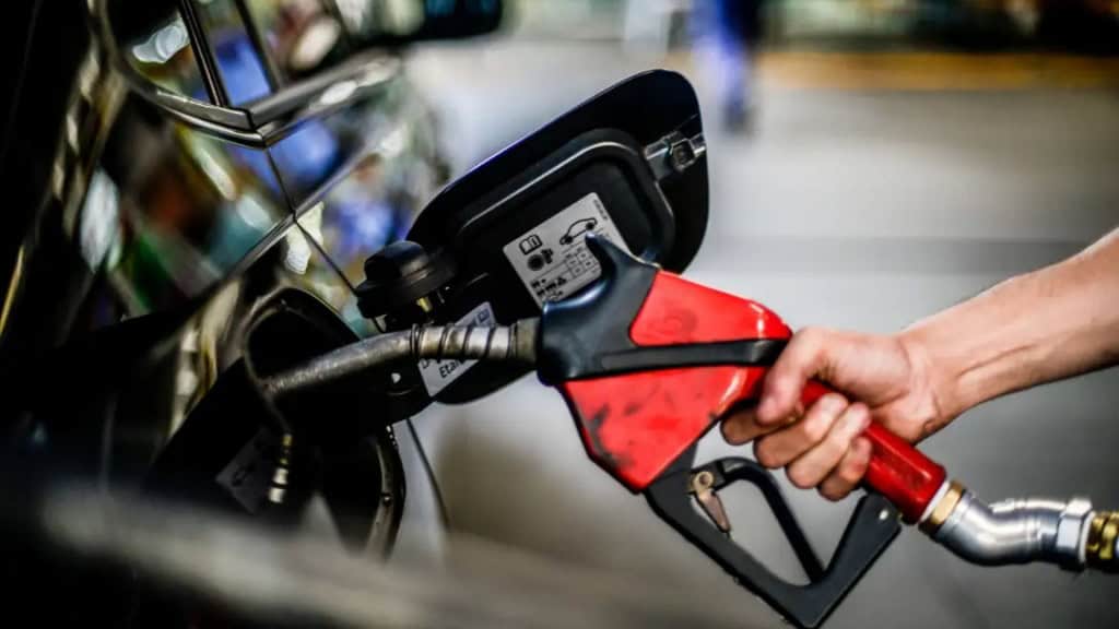 Frentista colocando combustível em carro estacionado em posto