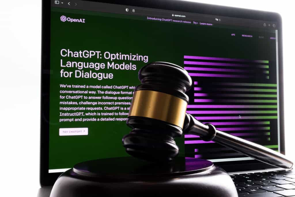 Ao fundo, site da OpenAI mostrando o ChatGPT; à frente, um martelo de juiz