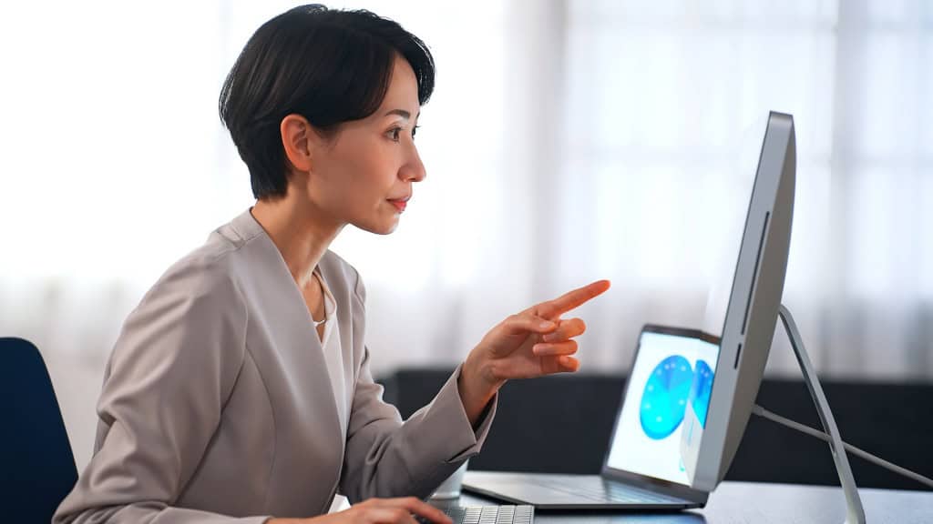 Mulher olhando e apontando para a tela de um computador