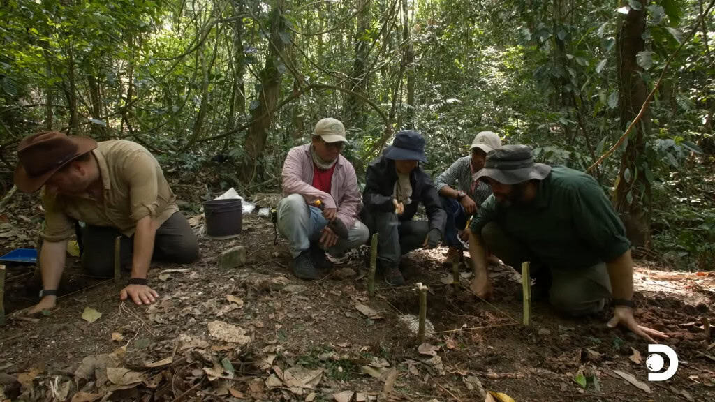 Grupo de pesquisadores em torno e uma escavação