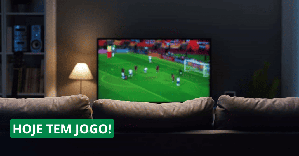 Ao fundo, TV passando um jogo de futebol; à frente, um sofá de costas