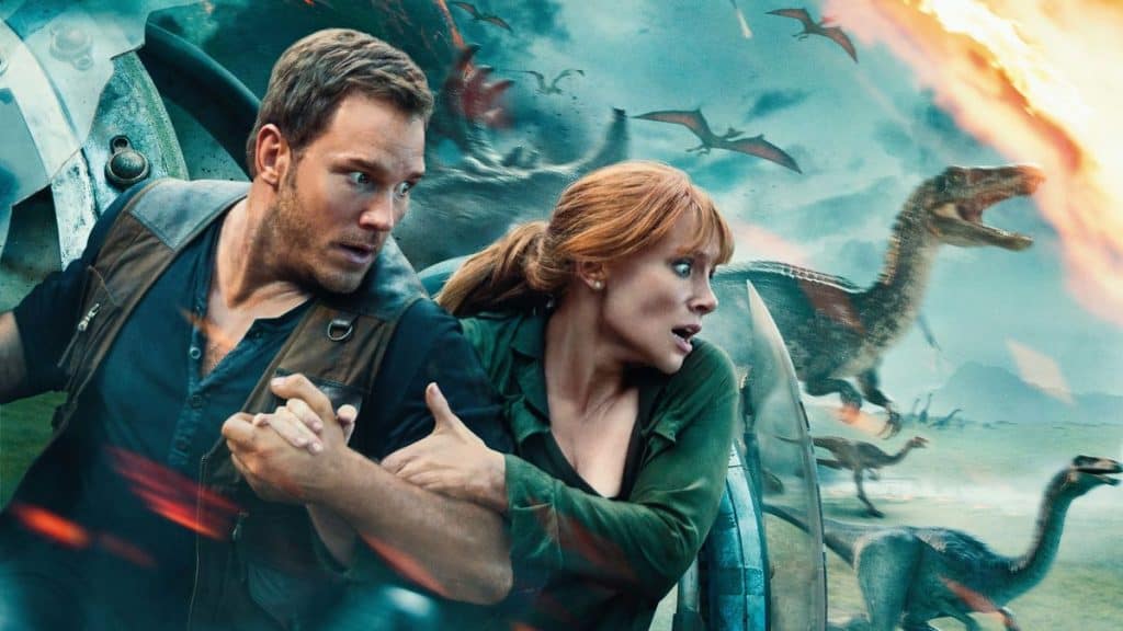 homem e uma mulher no primeiro plano com dinossauros ao fundo