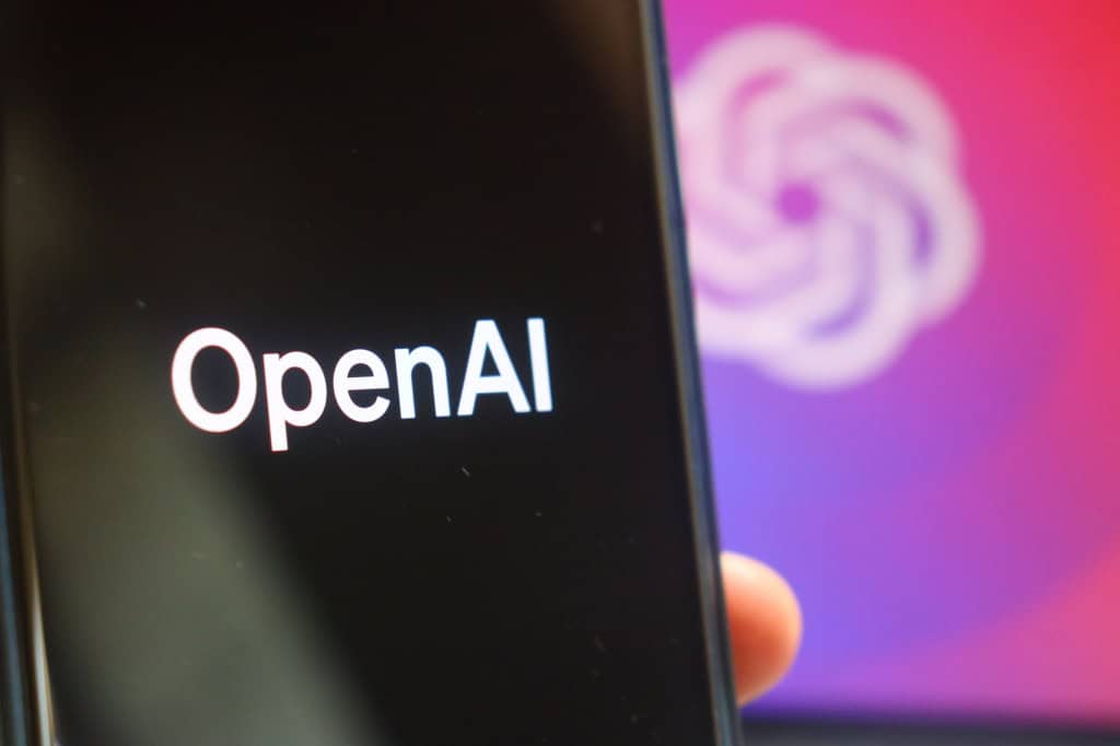 Logo da OpenAI em um smartphone e ao fundo