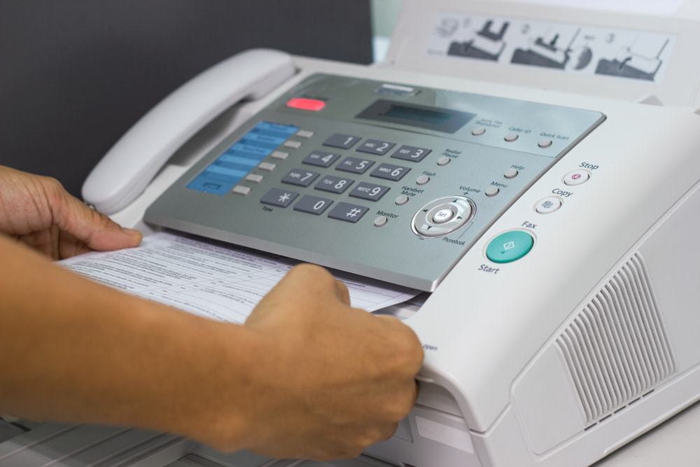 Homem usando uma máquina de fax no escritório