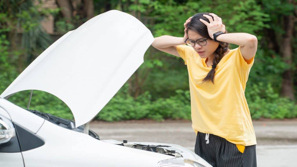 Jovem mulher estressada tendo problemas com a pane de seu carro na estrada e ela está esperando alguém que possa ajudá-la. Conceito de acidente de carro na estrada.