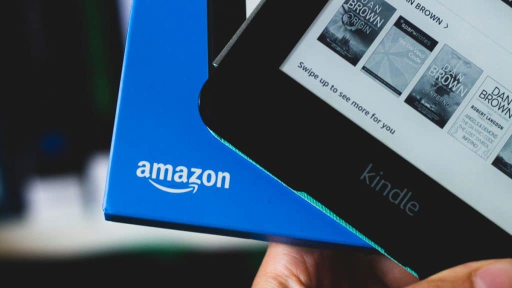 Imagem mostra um Kindle sendo retirado de uma caixa com o logotipo da Amazon