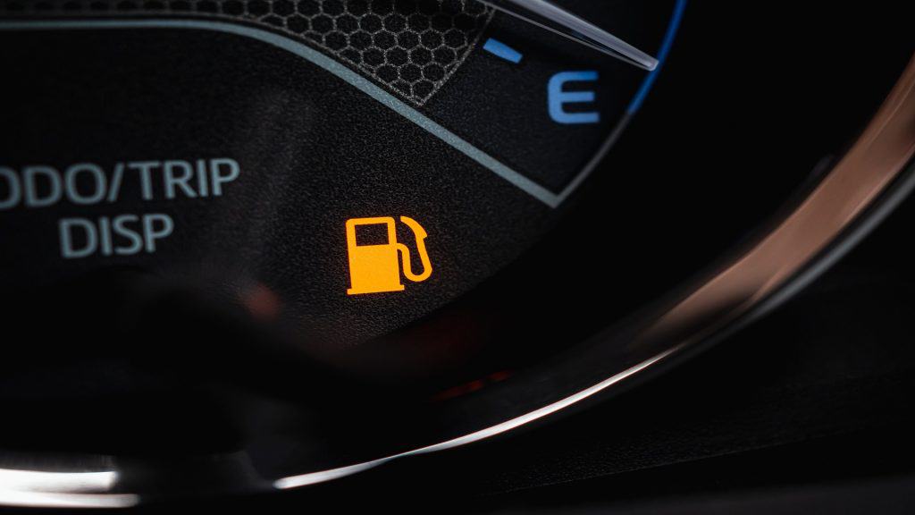 Close-up da luz de aviso de combustível vazio no painel do carro. Ícone da bomba de combustível. Mostrador de gasolina no painel do carro com sinal digital de alerta de falta de combustível aceso. Nível baixo de combustível exibido no velocímetro.