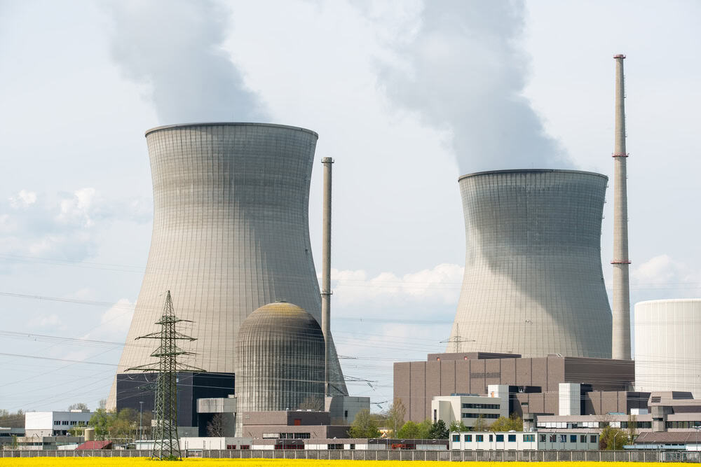 Usina nuclear com campo amarelo e grandes nuvens azuis