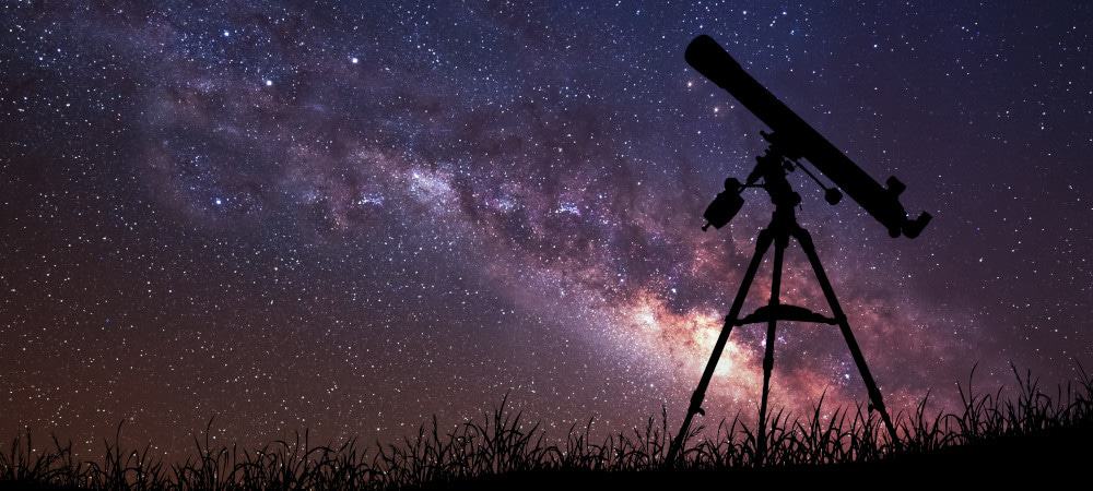 Céu estrelado contrastando com a sombra de um telescópio