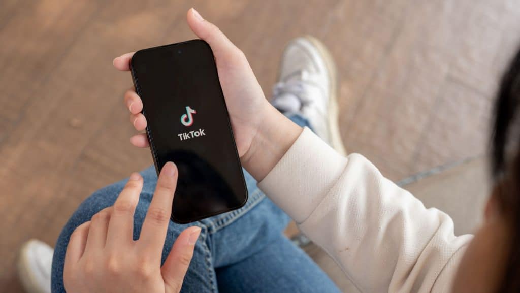 Pessoa segurando celular com logomarca do TikTok na tela – aquela que aparece ao abrir o aplicativo