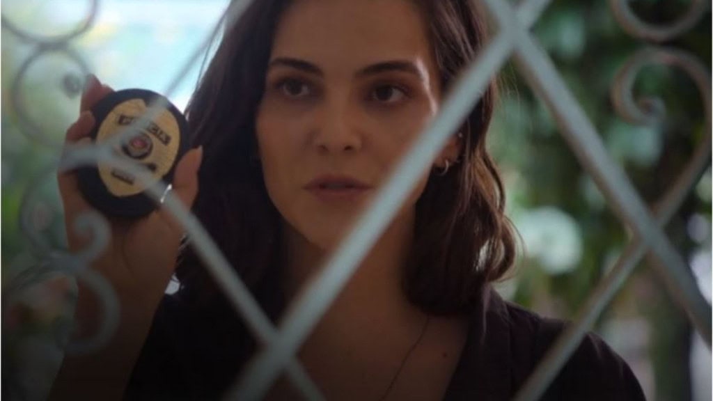 Mulher bonita com distintivo de policial mostrando através de uma tela de quadra