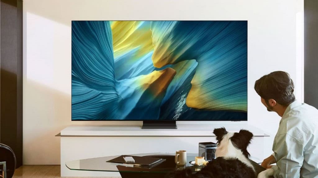 Homem e seu cachorro sentados numa sala olhando para smart TV OLED 2025 da Samsung