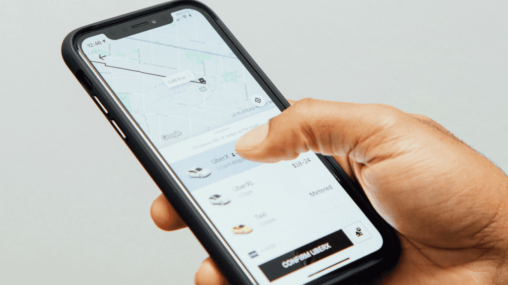 imagem mostra uma pessoa usando o aplicativo de celular Uber para chamar um carro