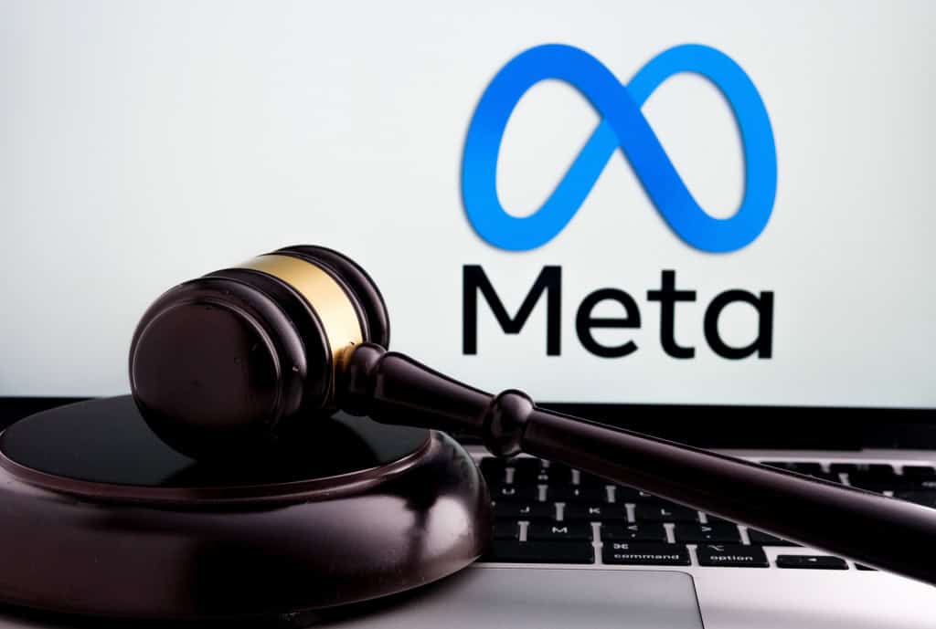 Ao fundo, logo da Meta na tela de um notebook; à frente, um martelo de juiz
