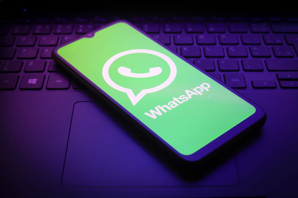 Logo do WhatsApp em um smartphone que está em cima de um teclado de notebook